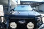 A Ford Ranger 4th generation with a front windscreen sun shade installed, equipped with a bull bar and LED spotlights.