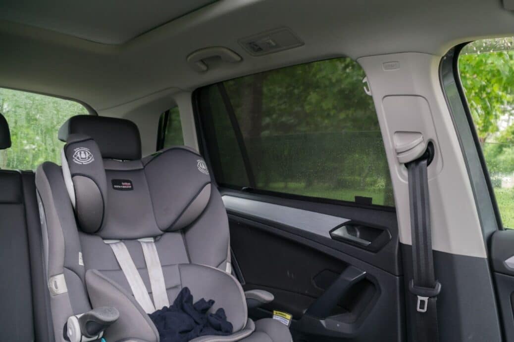 Interior of a Volkswagen Tiguan 2nd generation featuring a child's car seat and custom Snap Shades installed on the rear door window for shade and UV protection.