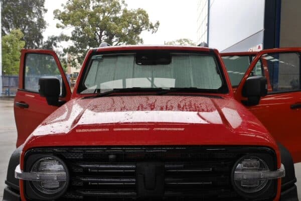 A red Tank 300 with front windscreen sun shades installed, parked in a rainy outdoor setting.