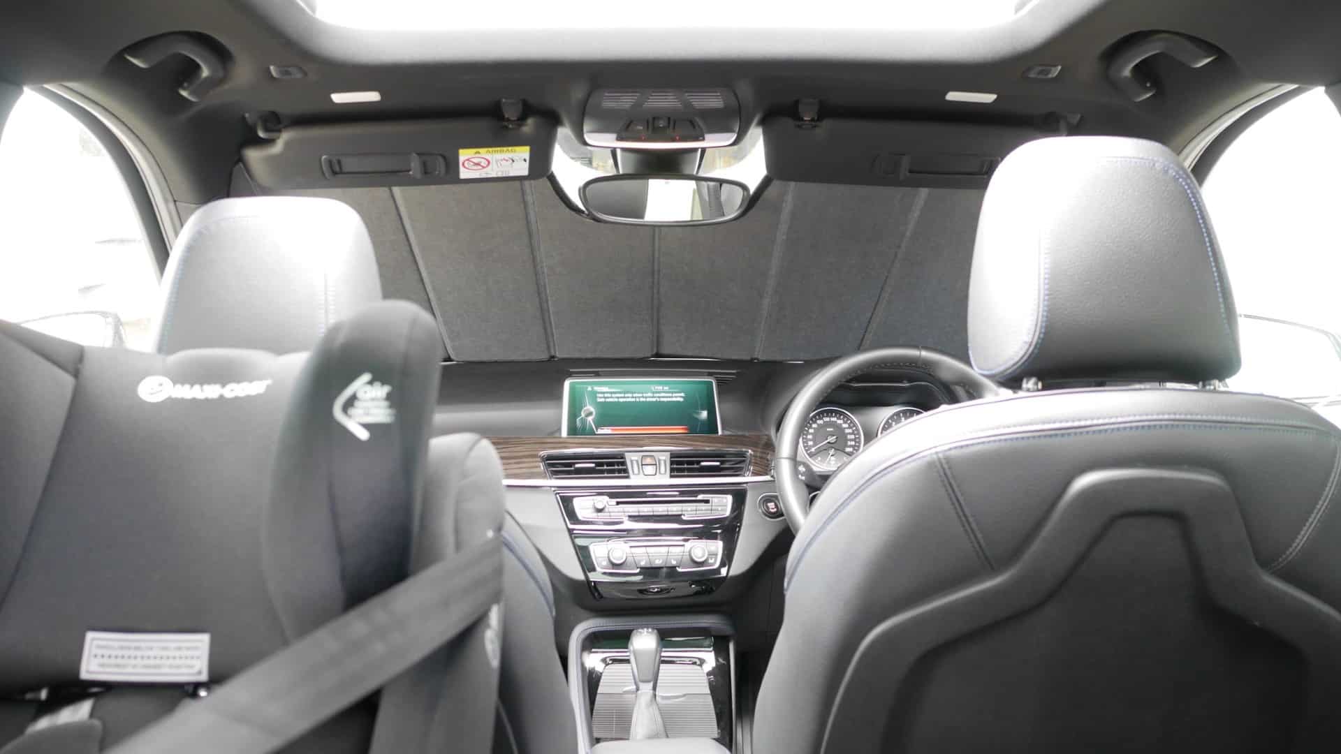 Interior view of a BMW X1 with a front windscreen shade installed, effectively blocking sunlight and reducing heat.