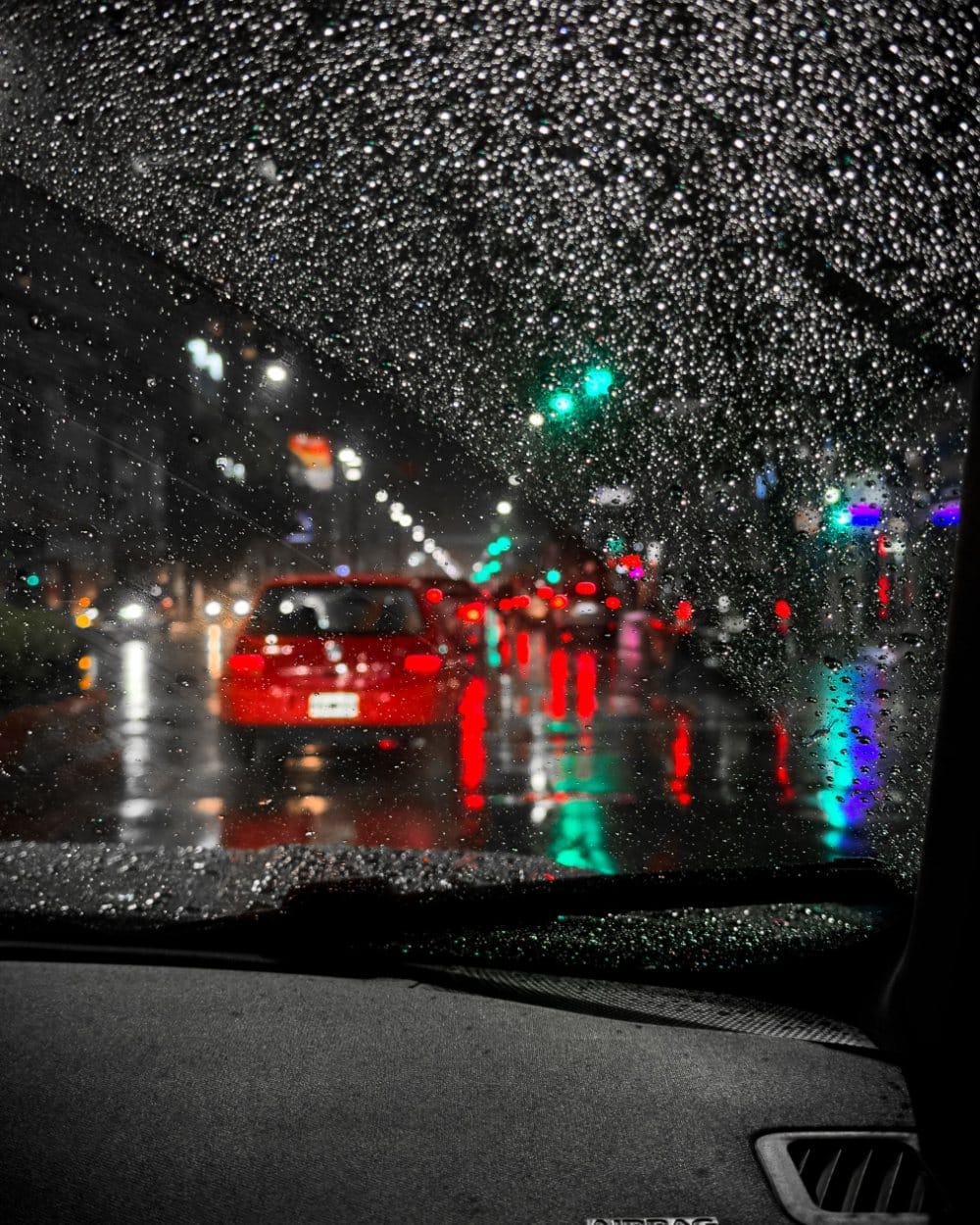 Rainy night traffic through a car windscreen