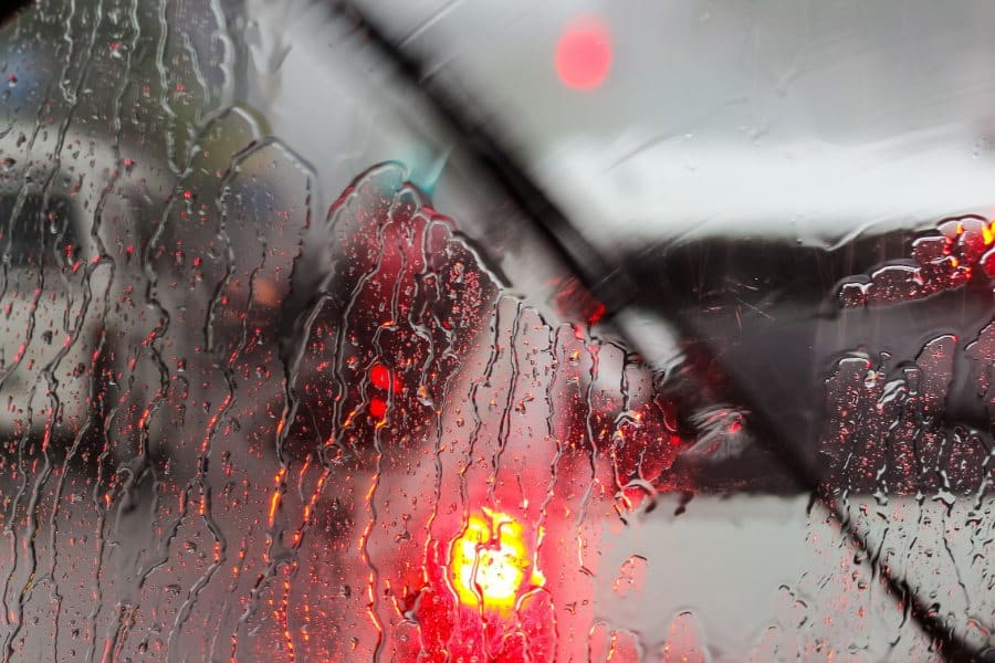 Wiper blade in the rain with blurred tail lights